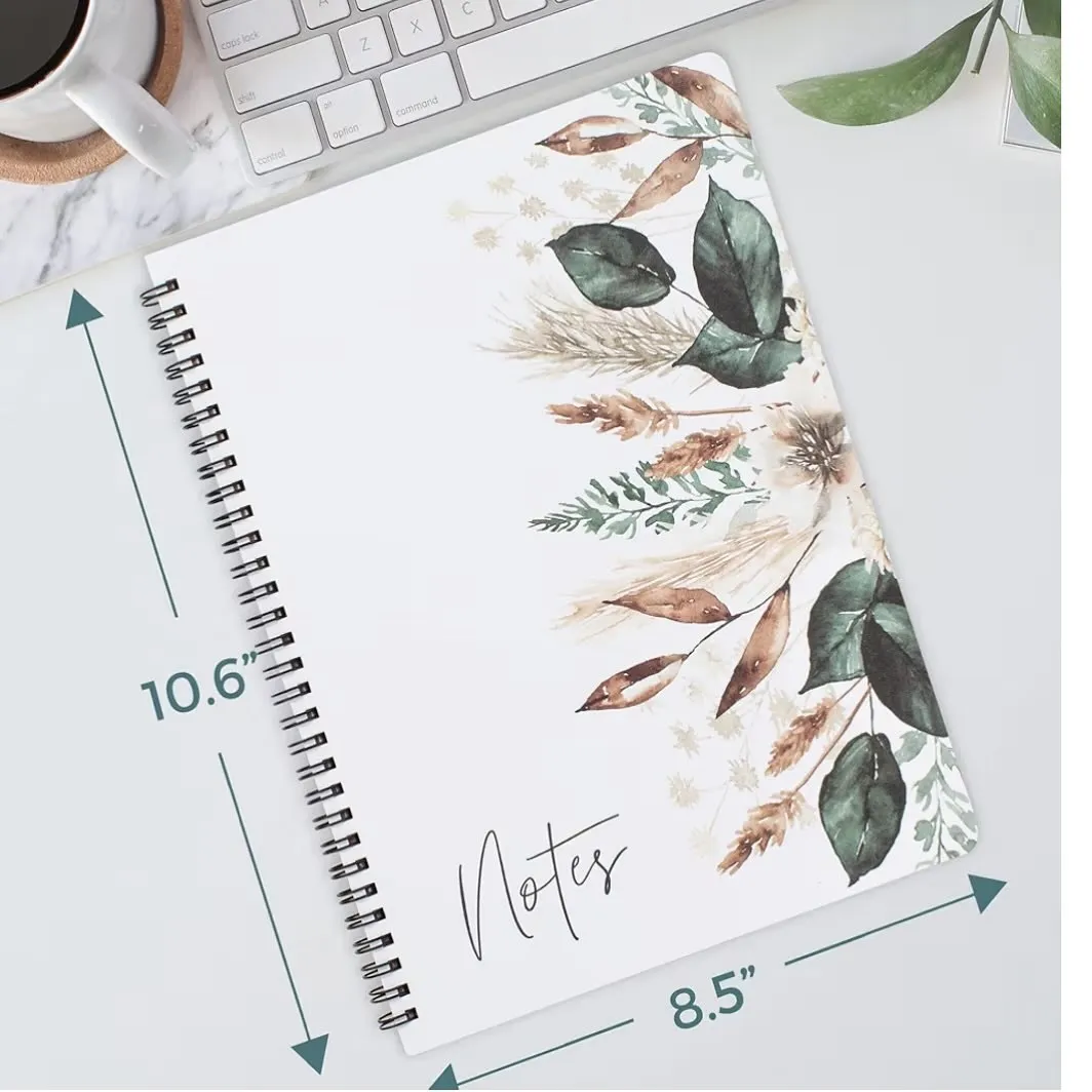 Large spiral notebook with autumn leaves and greenery on a desk